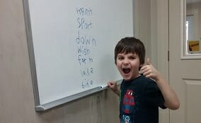 A photo of an excited young student learning how to spell and read at Foundations for Learning